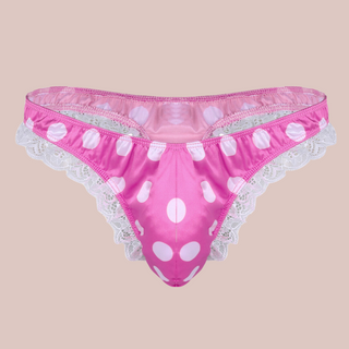 A bright pink satin men's female style knickers. They have a white spot pattern on the bright pink fabric, white lace edging to the legs and a thong style back.