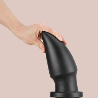 Showing the supersized anal plug attached by its base, it is being pulled gently to show its flexibility.