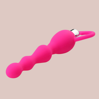 a bright pink beaded anal sex toy, shown lying down.